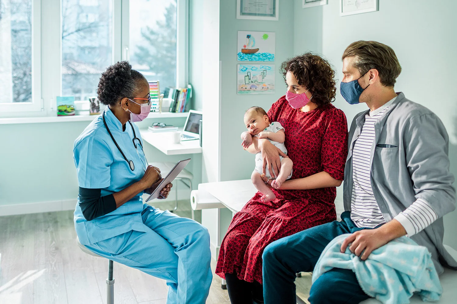 A nurse meets with parents and their newborn in a hospital room